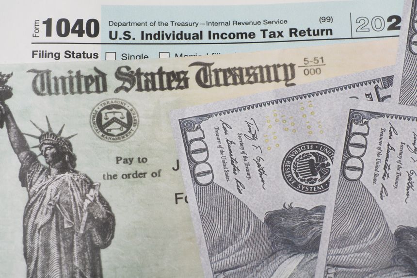 Prop US currency and treasury department check and top of 1040 tax form.