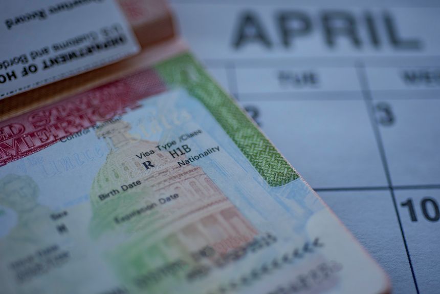 H1B visa (for specialty workers) stamp in passport, blurred april calendar on background. H1B visa program deadline concept. Close up view.
