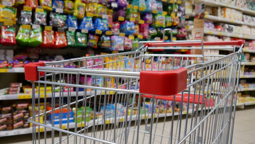 A shopping cart with a display case of sweets and gummies behind it