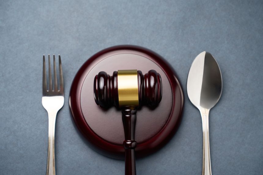 Judges gavel with fork and spoon on a dark background with copy space, close-up. Sanitary inspection, food law and justice concept