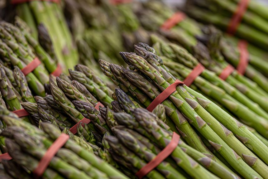 A close up of asparagus for sale on a market stall, with a shallow depth of field