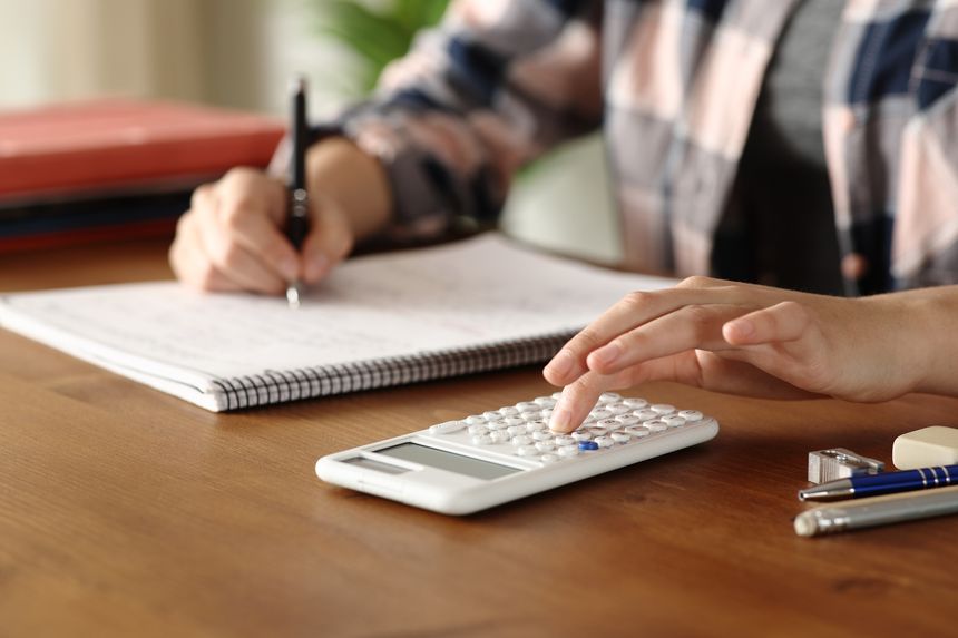 Close up portrait of a student hands using scientific calculator on a wooden table at home