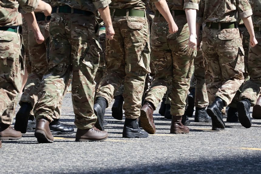 Close-up of military personnel marching in camouflage uniforms and boots. The focus is on their legs and disciplined movement, highlighting uniform patterns and footwear. The anonymous perspective makes it suitable teamwork, discipline, or service.