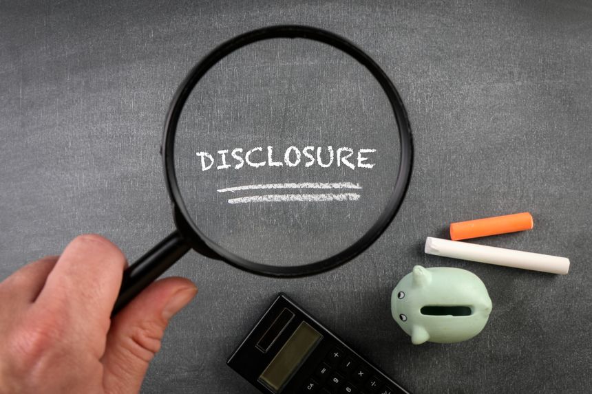 DISCLOSURE. Piggy bank, chalk pieces and magnifying glass on a blackboard.
