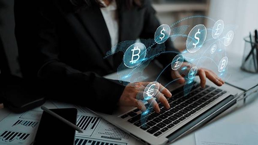 A business professional types on a laptop while various virtual currency icons hover above, illustrating the dynamic world of finance and digital transactions in a modern office setting.