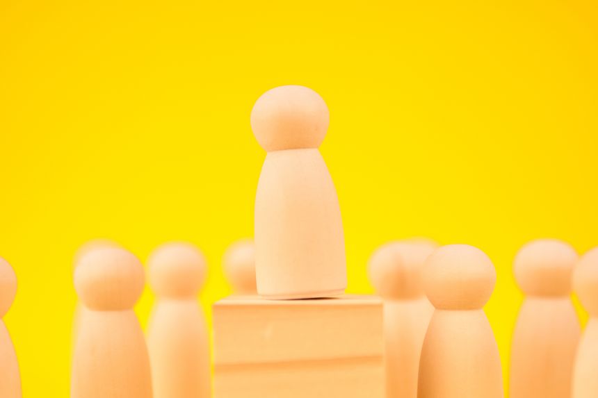 Figure elevated above a group to illustrate leadership, authority, and recognition, indicating earned influence and visible trust from peers and teams.