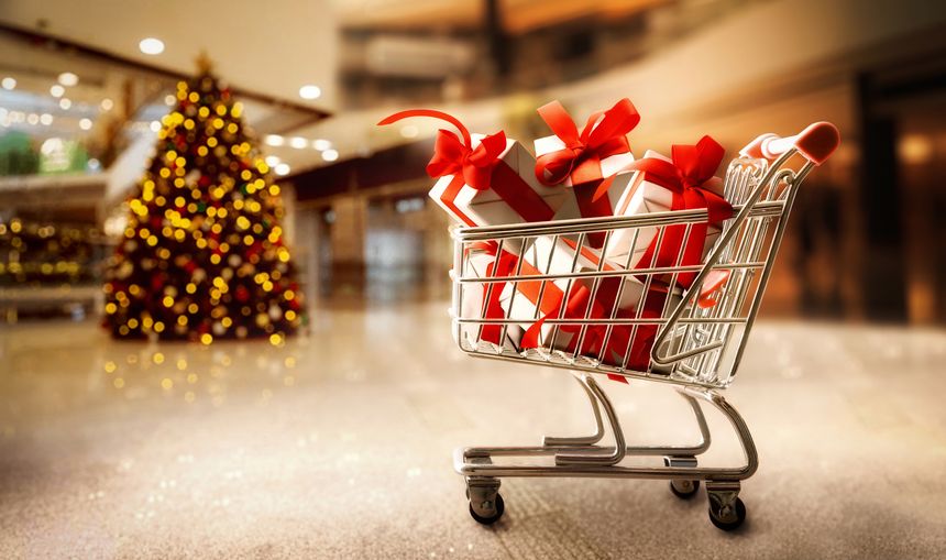 Holiday gift shopping concept with shopping cart full of gift packages wrapped in white paper and red ribbon in shopping center.