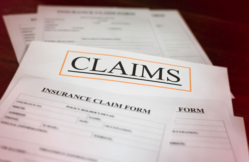 In selective focus of CLAIMS letter on white paper,at the middle of blurred Insurance Claim form,blurry light around