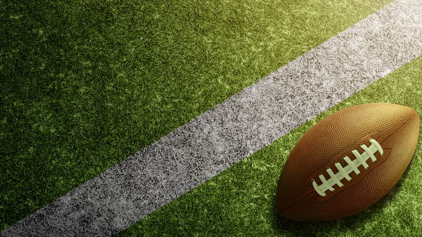 American football ball on the green field of an American football stadium. Concept of sport