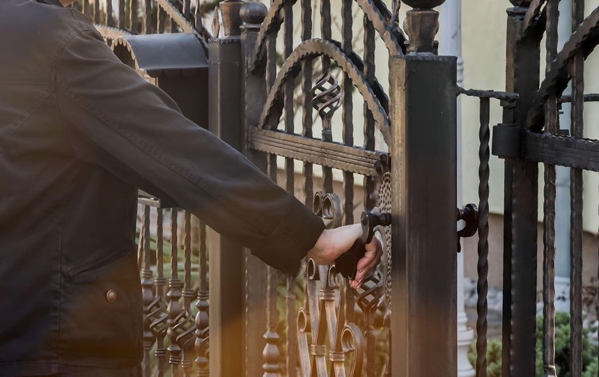 Woman Hand opening Wrought metal fence gate