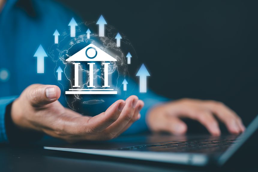 Hand holding a virtual bank icon surrounded by arrows and percentage signs, symbolizing rising interest rates, financial trends, and banking sector growth.