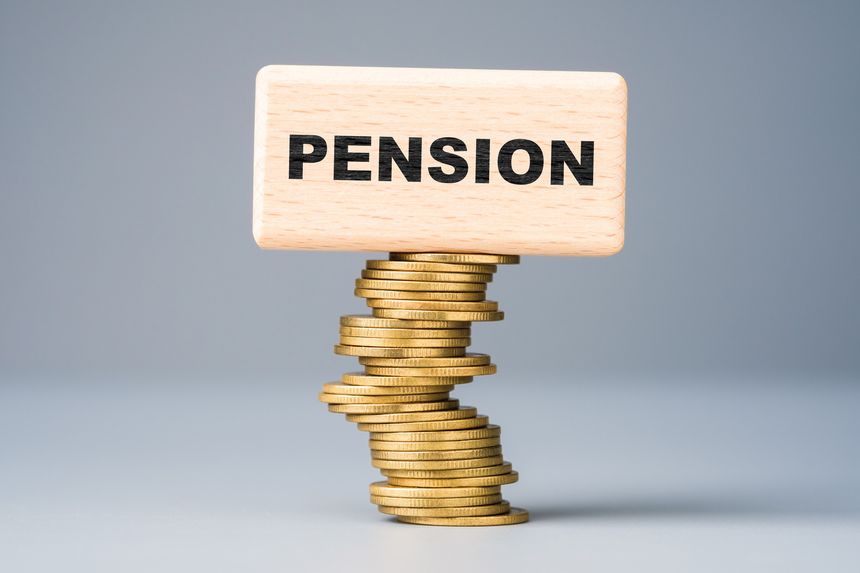 Wooden block labeled pension balanced on unstable stacks of coins, symbolizing financial insecurity, pension crisis, and the fragile foundation of retirement systems