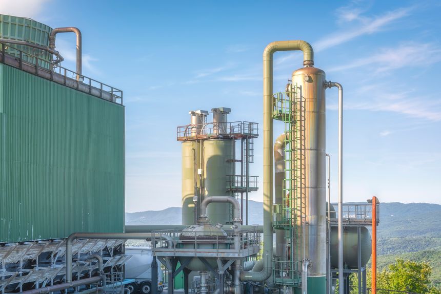 Industrial landscape view of a Geothermal Complex in Larderello, Tuscany, the world's oldest geothermal energy production site. Large pipes, cooling towers and rolling hills.