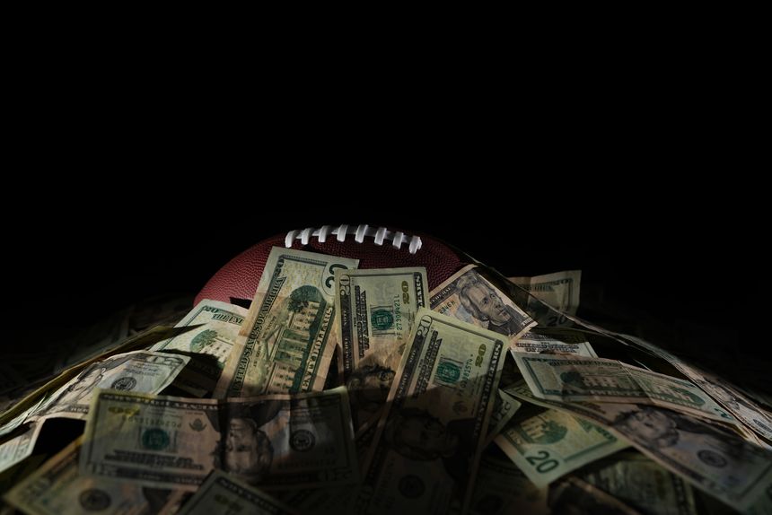 A football covered in a pile of cash, on black background
