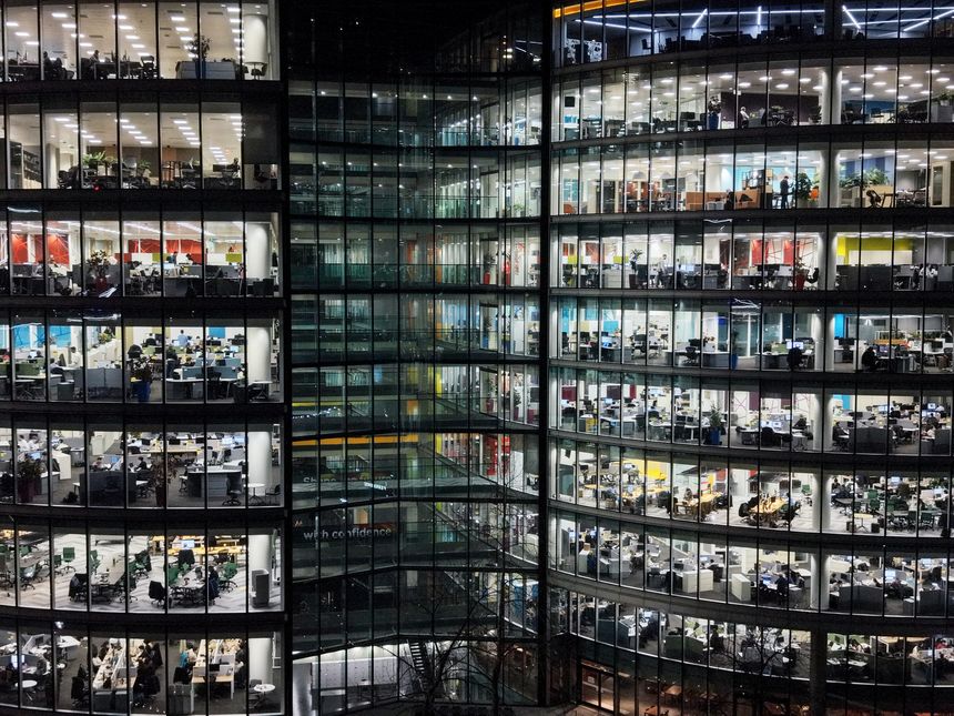 Fragment of the glass facade of a modern corporate building at night. Modern glass office in city. Big glowing windows.