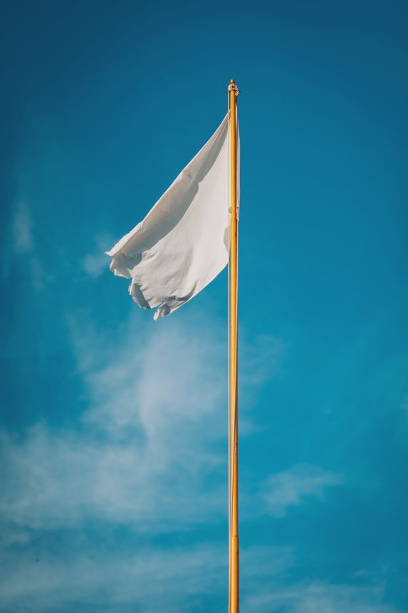The flag dances gently in the breeze, its bright fabric contrasting beautifully with the clear azure sky. This serene scene evokes a sense of calm and unity.