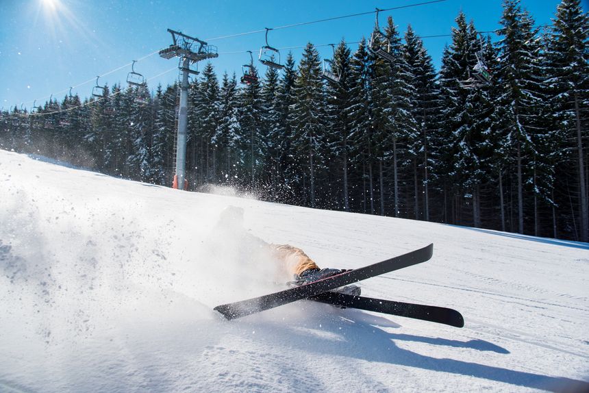 Skier falling on the slope on fresh powder snow at winter resort adventure extreme adrenaline active lifestyle concept
