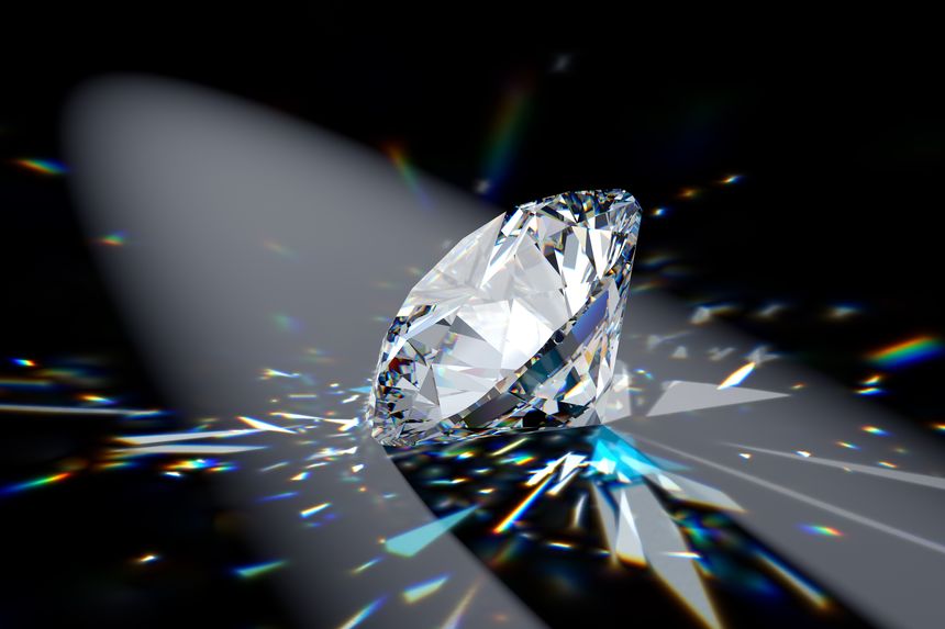 Round brilliant cut diamond in a spotlight on black background with contrast shadows and colorful refraction rays of light