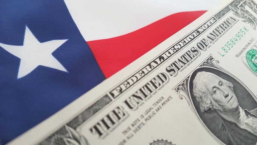 A close up shot of the Texas flag and a new one dollar bill