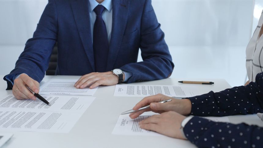 Business people reviewing contract during a meeting, pointing at specific clauses and discussing potential amendments before signing the agreement.