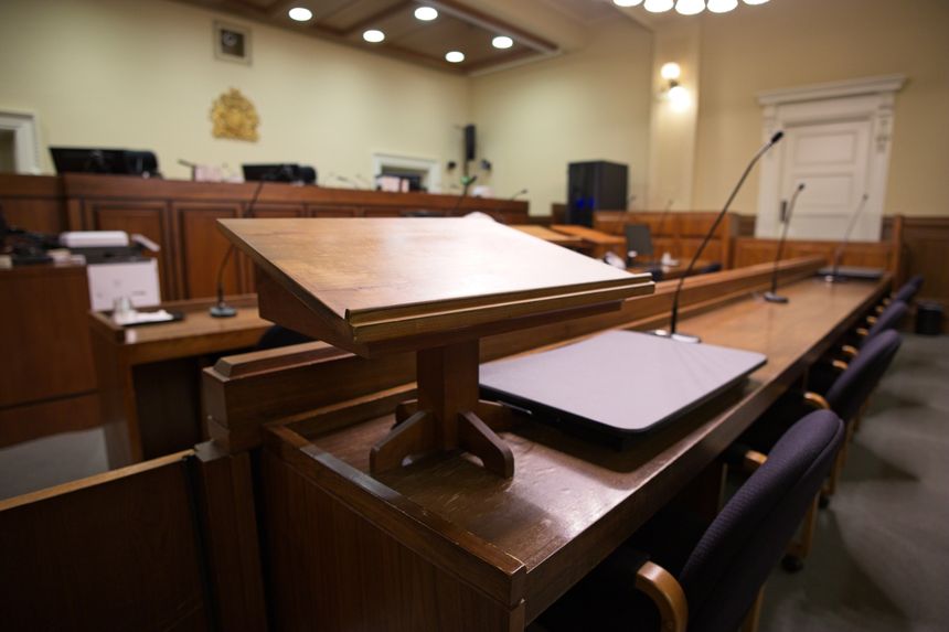 Empty courtroom with a wooden witness stand and microphones, showing a formal legal setting for trials, hearings, justice, law, and public institutions.