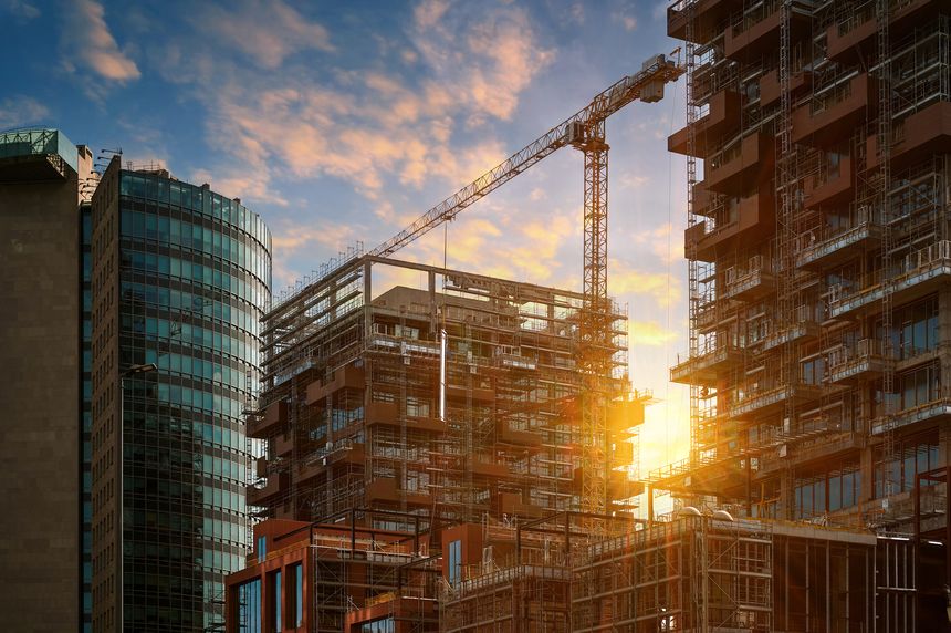 Construction of a new modern residential complex. High-rise building with decorative elements, against the backdrop of a beautiful sunset sky.