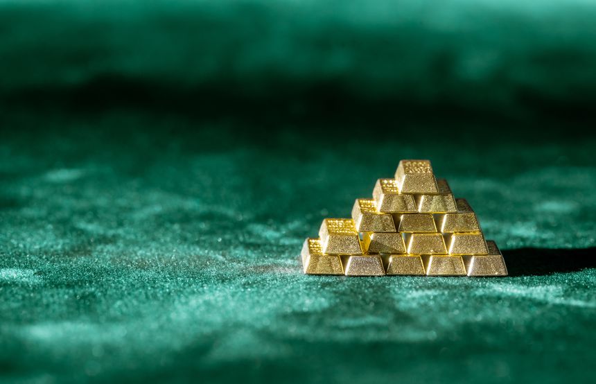A small pyramid stack of shiny gold bars arranged neatly on a textured green velvet surface symbolizing wealth, investment, and trading concepts under soft lighting with sharp focus