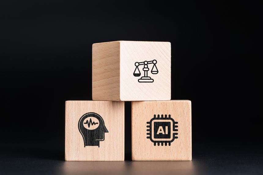 Wooden blocks showing AI chip, human head, and justice scale, representing the comparison of bias and fairness between artificial intelligence and human decision-making