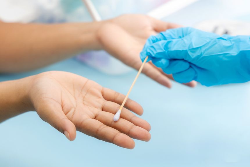 Scientist's hand holding a cotton swab and wiping dipped in diluted rubbing alcohol to hands and fingers. Cleaning dirty fingers to test for disease for food safety is a process of measuring in lab.