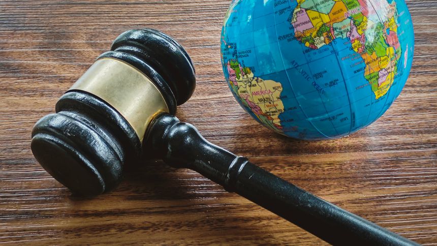 Gavel Lying Across a Small World Globe on a Dark Wooden Table, Symbolizing International Law, Global Justice, Environmental Policy, and Human Rights.
