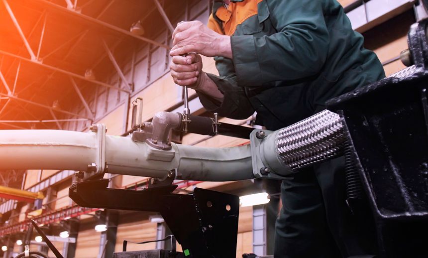 Technician repairs military equipment using tools in a well-equipped manufacturing plant focused on defense technology.