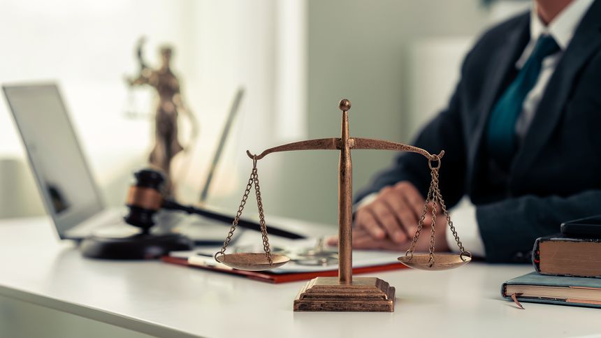 Lawyers working with documents Law, advice and justice concept, lawyer in suit signing legal document at table with justice scale, close-up
