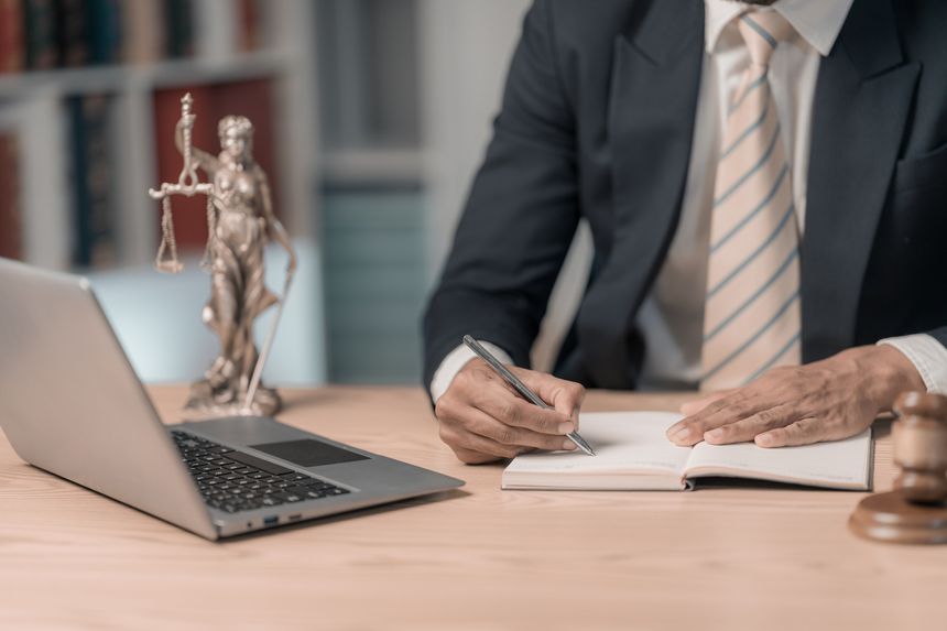 Lawyers working with documents Law, advice and justice concept, lawyer in suit signing legal document at table with justice scale, close-up