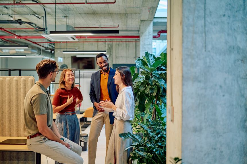 Multicultural businesspeople talking and smiling during a meeting in a modern office with plants
