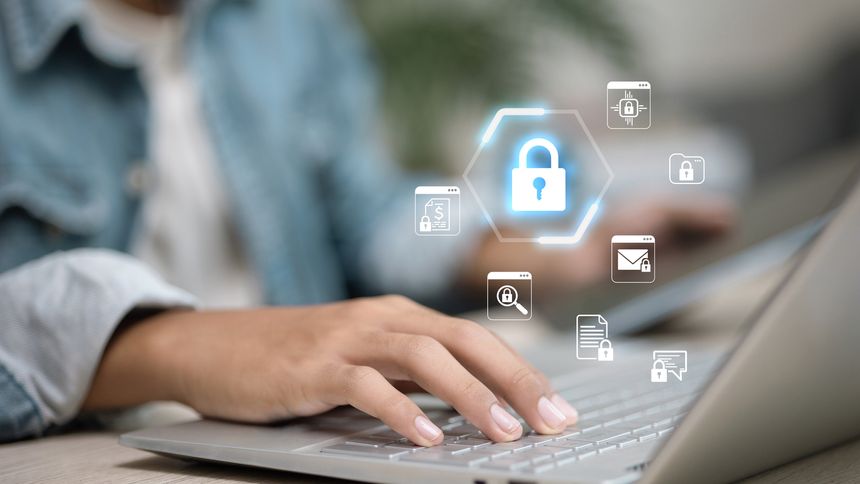Close-up of hand typing on laptop with glowing digital padlock and security icons, representing cybersecurity, online privacy, data protection, and safe internet access for business.