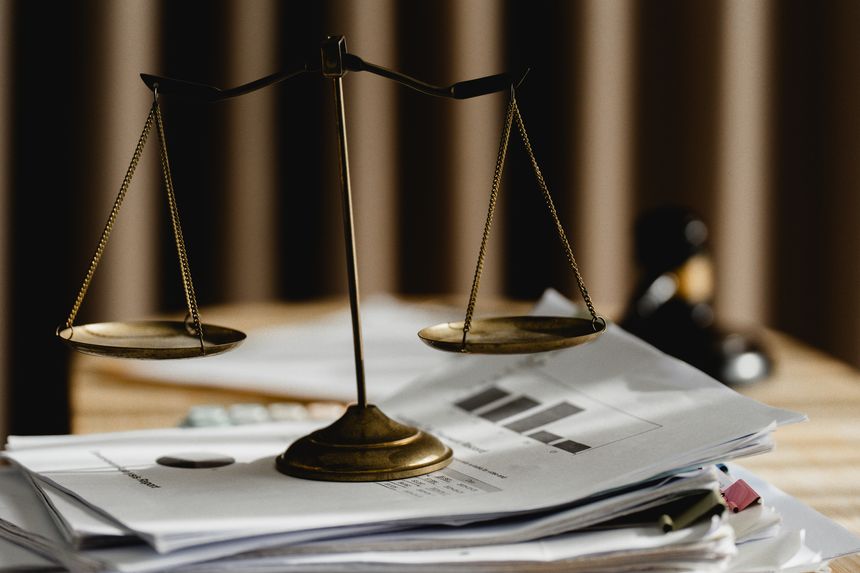 Justice scale placed on organized legal documents symbolizes legal compliance, contract management, document review, business law, professional legal services, and corporate governance.