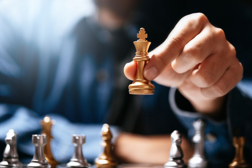 Strategic business move. Businessman holding golden king chess piece on board. Success, leadership, and visionary planning concept for corporate competition and marketing strategy.