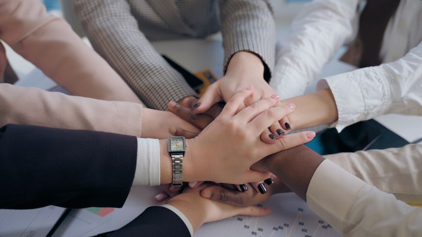 African American Japanese Hispanic multiethnic business women females team girls coworkers businesswomen hands arms folded in unity gesture cooperation teamwork partnership documents table at office. High quality 4k footage