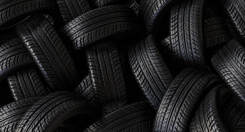 Many black car tires showing their dark rubber surface and prominent tread pattern