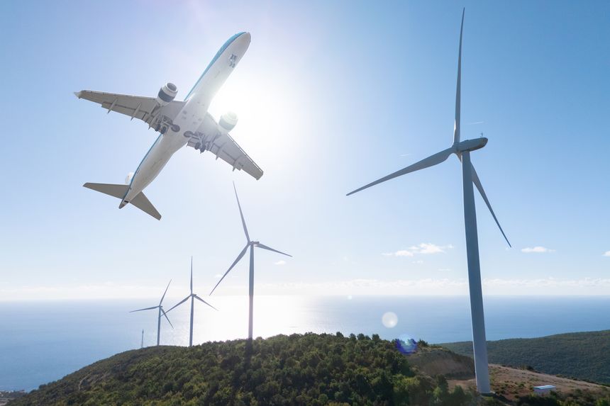 Airplane flies above a wind farm with modern turbines. Global transition to sustainable power.