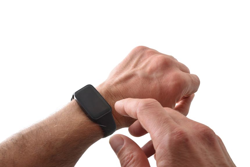 Detail of a black activity watch worn on a man's wrist and hand interacting with it, isolated on a white background