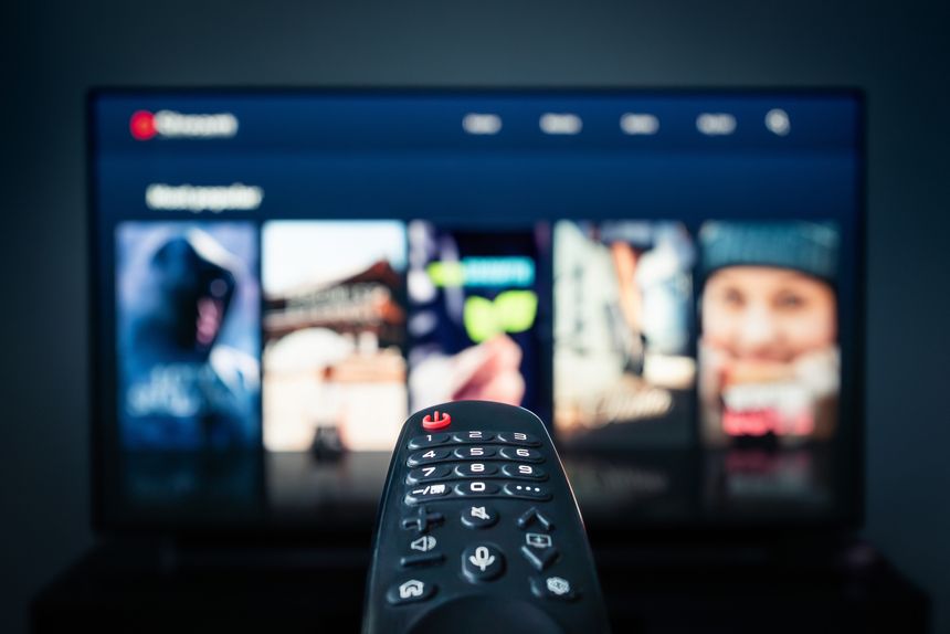 TV movie stream watching. Film catalogue. Streaming service content selection. VOD subscription. Choosing series from library mockup in screen. Remote control closeup. Television night at home.
