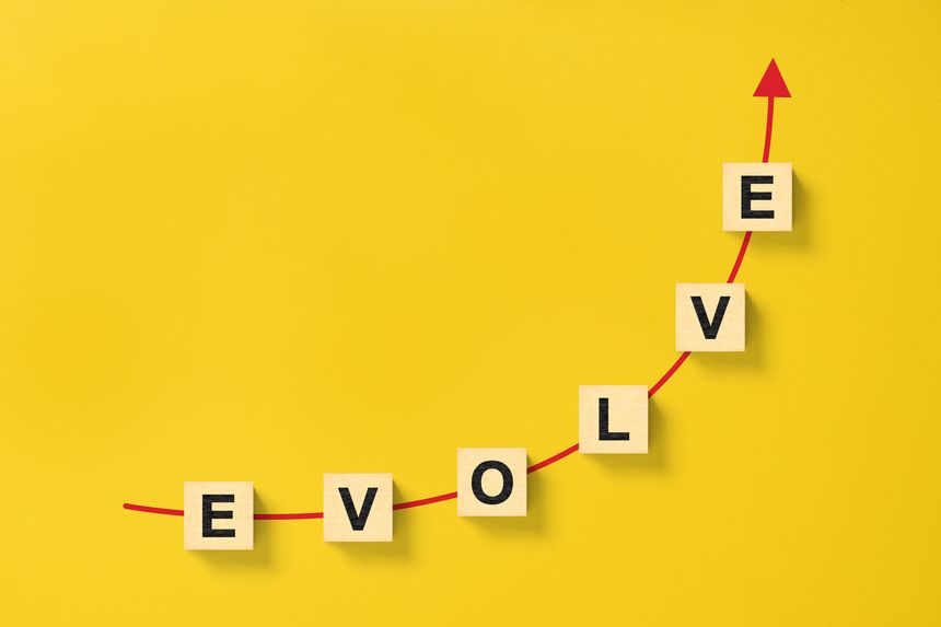 Wooded cube block on yellow background with word EVOLVE and copy space for your text
