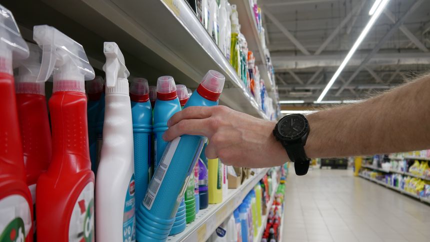 A man takes a bottle with a detergent