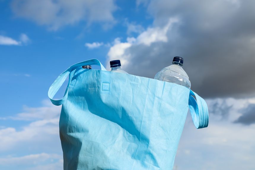 Reusable bag with empty plastic bottles set against a bright sky, highlighting recycling practices, zero-waste lifestyle, and environmental responsibility.