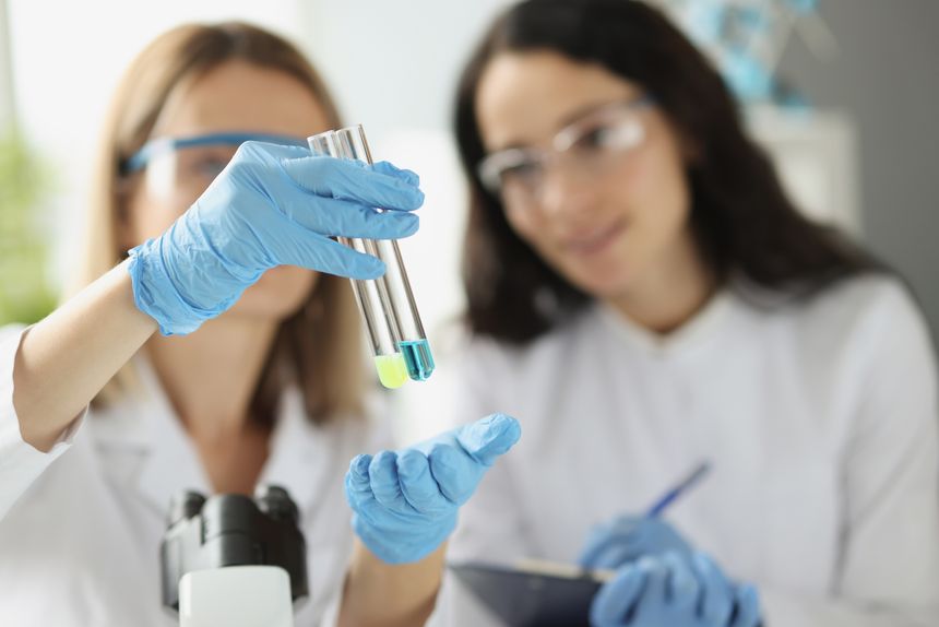 Woman scientist chemist showing test tubes with blue and yellow liquid in laboratory closeup. Pharmaceutical industry concept