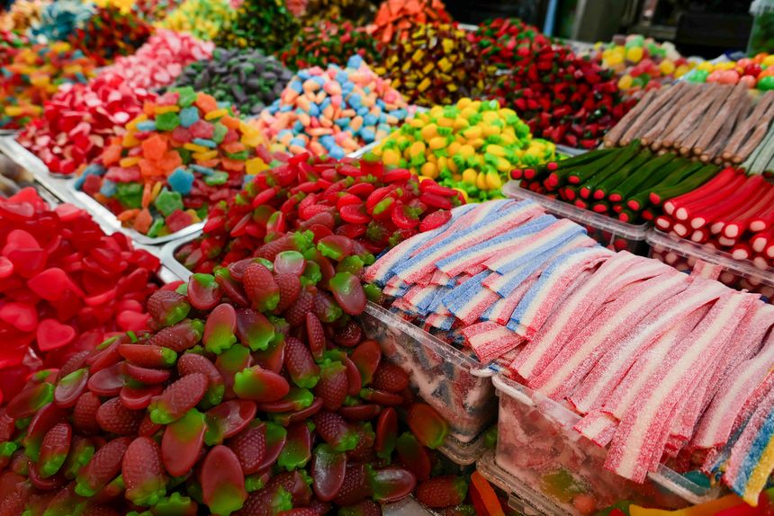 A vibrant assortment of colorful gummy candies and sugary treats at a market stand, illustrating products that may contain artificial dyes soon to be banned under new FDA regulations.