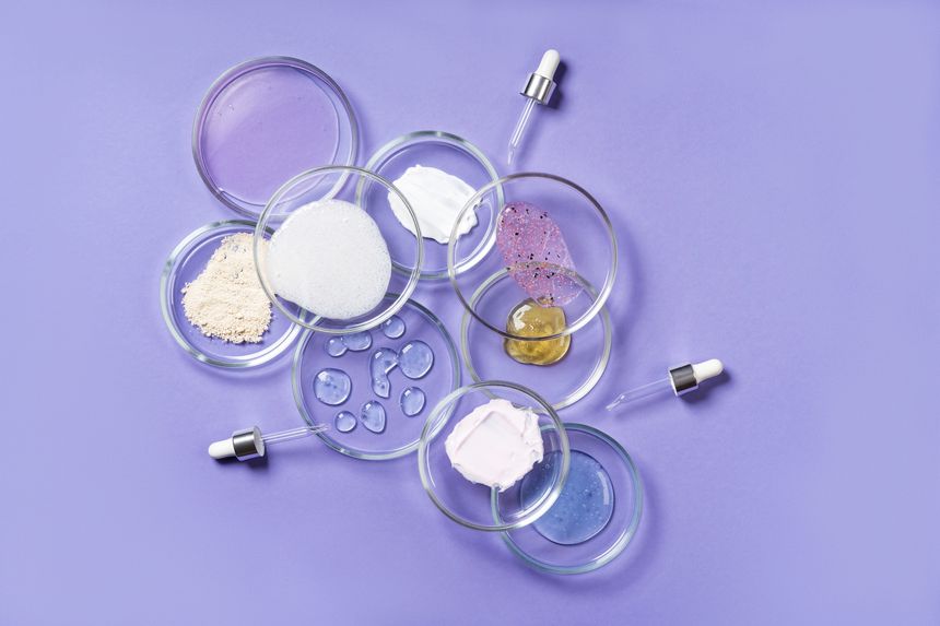 Cosmetic products, scrub, face serum and gel in many petri dishes on a pink background. Cosmetics laboratory research concept