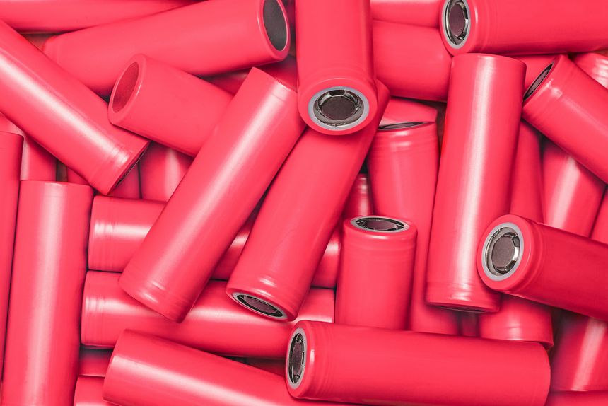 top view of red lithium-ion battery cells arranged in a random pattern. Ideal for demonstrating the technical aspects and concepts of electric vehicles, modern waste recycling, and manufacturing.