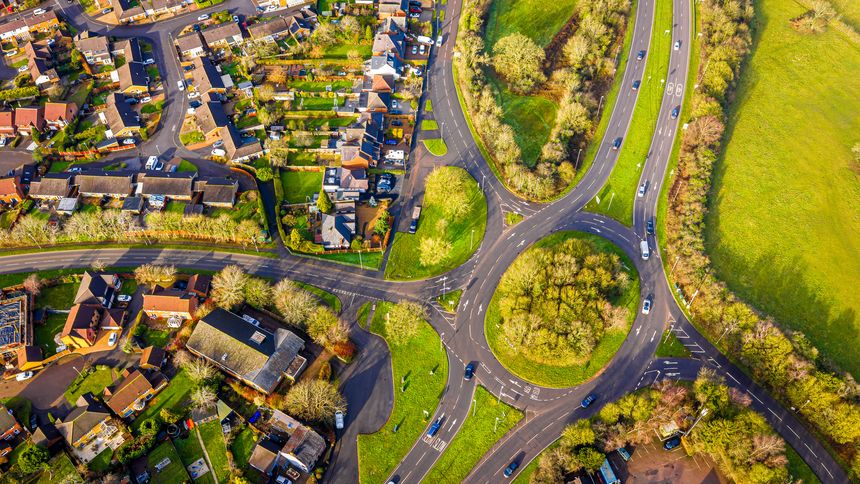 Aerial view of Field Head, Leicestershire showing homes, roundabout roads and green farmland at golden hour; ideal for real estate, urban planning, transport and lifestyle campaigns